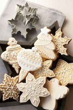 some cookies are sitting on a table next to cookie cutters and christmas decorations in front of them