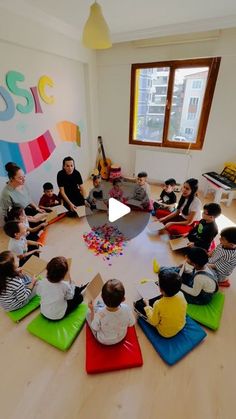 a group of children sitting in a circle on top of yoga mats and playing with toys