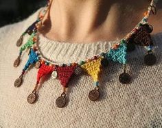 a woman wearing a multicolored crochet necklace with coin charms on it