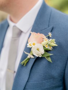 a man wearing a blue suit and white flowers on his lapel flower pin,