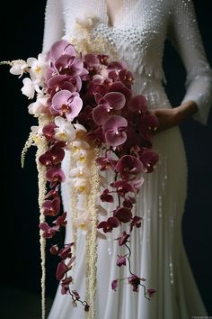 a woman in a white dress holding a bouquet of orchids and other flowers on her wedding day