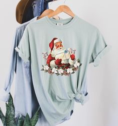 Welcome to Pink Pepper Designs Co.! I hope you find that one thing that expresses YOU perfectly! We just love this Vintage Santa Claus T Shirt, with the trendiest Retro Christmas Holly Jolly Vibes this side of December 25th. For all those looking for the cutest Christmas shirts in super trendy Comfort Colors Tees, come and check out our whole collection! The Comfort Colors 1717 is the ultimate garment-dyed t-shirt, made 100% with ring-spun cotton. The soft-washed, garment-dyed fabric brings extr Christmas Cotton Short Sleeve Shirt, Christmas Cotton Graphic Tee Shirt, Christmas Crew Neck Cotton Shirt, Christmas Graphic Tee Shirt In Cotton, Christmas Cotton Shirt, Holiday Cotton Graphic Tee Shirt, Holiday Cotton Tops With Funny Print, Holiday Cotton Shirt With Crew Neck, Cotton Graphic Tee Shirt For Holidays