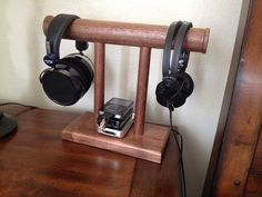 a wooden table topped with headphones and a cell phone on it's stand