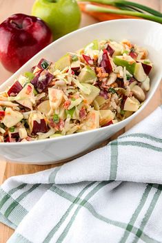 a white bowl filled with salad next to an apple