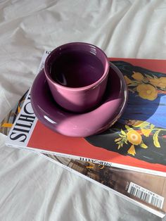 a purple cup and saucer sitting on top of a magazine next to each other