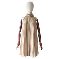 An iconic beauty to behold, this original 1960's gold lurex dress, set off by accordion pleats and gold braiding along the neckline, is a true piece of fashion history. The high collared neckline, fastens along the left hand side with press studs and hook and eye fastenings. The collar is accented by pleated and gathered edgings along the top and bottom, framing a simple gold lurex panel. The elegant racer back cut of the dress sets off the sleeveless design, which draws the eye to the magnifice 1960s Cocktail Dress, Vintage 1930s Dress, Iconic Beauty, Lurex Dress, Accordion Pleats, Bolero Dress, 1930s Dress, Dress Sets, Keyhole Dress