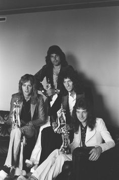 an old black and white photo of four people holding trophies in front of their faces