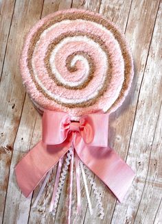 a pink and brown candy lollipop on top of a wooden table with ribbon