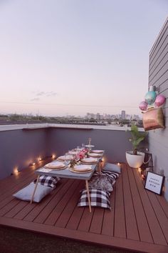 an outdoor table set up on a deck with candles and balloons in the sky above