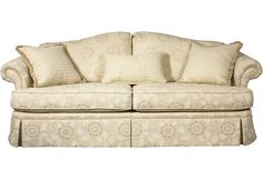 a couch with several pillows on top of it and a skirted sofa under the seat