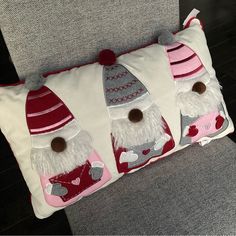 a pillow with three gnomes on it sitting on a couch next to a chair