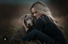 a woman sitting in the grass with her dog