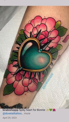 a heart tattoo with flowers on the arm