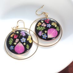 These pressed flower earrings are handmade and feature real botanicals in resin. These wildflowers are colorful and pop against the black background. Available in gold or silver, they feature butterfly rose petals, buttercups, fern leaf, alyssum, forget-me-not flowers, and more! Perfect for the nature lover, plant lover, gardener, or general flower lover in your life. They make a great choice for garden parties, outdoor wildflower weddings, or even just as an everyday way to emanate Spring! Dime Multicolor Flower Shaped Jewelry With Pressed Flowers, Multicolor Flower Jewelry With Pressed Flowers, Gold Floral Print Flower Earrings, Botanical Drop Earrings With Pressed Flowers, Botanical Style Drop Earrings With Pressed Flowers, Botanical Pressed Flowers Drop Earrings, Nickel-free Botanical Flower Earrings, Botanical Birth Flower Dangle Earrings, Gold Floral Print Earrings As Gift