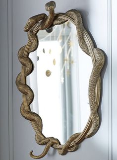 a mirror hanging on the side of a wall next to a door with a rope wrapped around it