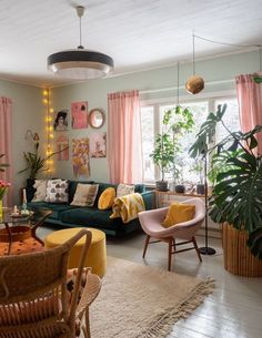 a living room filled with furniture and lots of plants on the wall next to windows