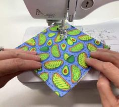 two hands are using a sewing machine to sew an avocado print fabric