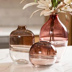 three vases with flowers in them sitting on a counter top next to each other