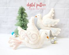 two white doves sitting on top of a counter next to a small christmas tree