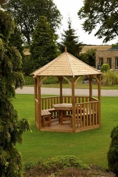 a wooden gazebo sitting on top of a lush green field