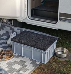 there is a dog bowl and some shoes on the ground next to an rv door