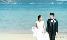 a bride and groom walking on the beach