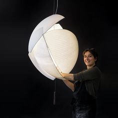 a woman is holding up a lamp that looks like an object with a curved body