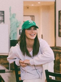 a woman sitting at a table wearing a green hat