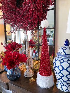 red and white christmas decorations are on a table in front of a mirror with candles