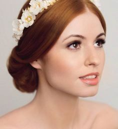 a woman with red hair wearing a white flower headband on top of her head