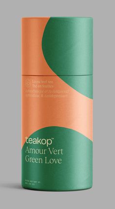 an orange and green canister with the words teakop on it, in front of a gray background