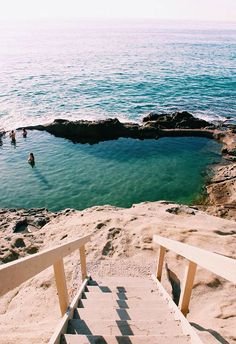 stairs lead down to the beach with people swimming in the water