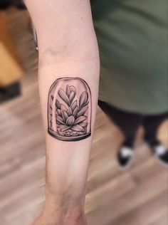 a black and white photo of a plant in a glass vase on the arm,