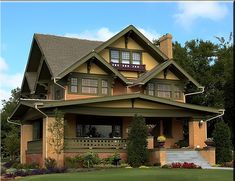 a large brown house with lots of windows on it's roof and front porch