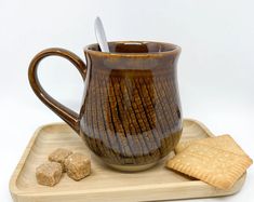 a coffee cup and crackers on a wooden tray