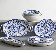 the blue and white dishes are set on the table with one bowl, two spoons and three plates