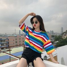 a woman sitting on top of a roof next to a tall building with buildings in the background