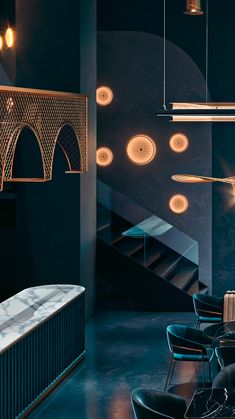 a room filled with black chairs and lights hanging from the ceiling next to a stair case