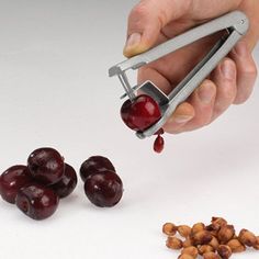 a hand holding a pair of tongs with cherries on it and nuts in the foreground