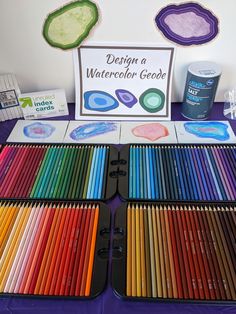 there are many different colored pencils on the table with a sign that says design a watercolor gooe