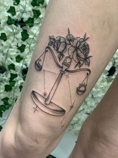 a tattoo on the leg of a woman with a scale and flowers in it,