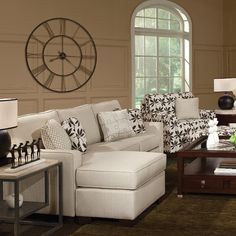 a living room filled with furniture and a large clock mounted to the wall above it