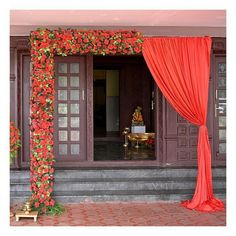 an entrance decorated with red flowers and greenery for a wedding ceremony at the same time