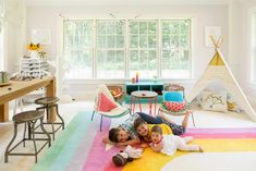 two children are laying on the floor in front of a teepee tent and table