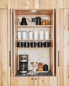 an open cabinet with coffee cups and other items on it, which is also in the kitchen