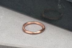 Made with SCS recycled rose gold, this organic and irregularly shaped ring gently glows from the satin finish. Looks beautiful alone, or stacked, a unique wedding band. Design Specifications: - Type: Ring - Material: SCS recycled rose gold - Width: 2.2-1.2mm - Thickness: 1.2mm - Finish: Satin Hammered Rose Gold Stackable Rings For Wedding, Wedding Stackable Hammered Rose Gold Rings, Wedding Hammered Rose Gold Stackable Rings, Rose Gold Hammered Wedding Rings, Rose Gold Square, Unique Wedding Band, Artisan Rings, Band Design, Hammered Rings