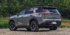 the rear end of a gray toyota rav parked on a gravel road in front of trees