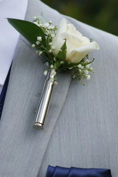 a boutonniere with a white rose and baby's breath