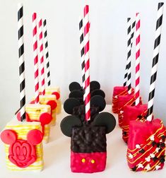 some mickey mouse candles are lined up on a white table with red and black striped straws