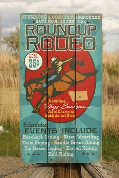 a wooden sign sitting on the side of a road in front of a grass covered field